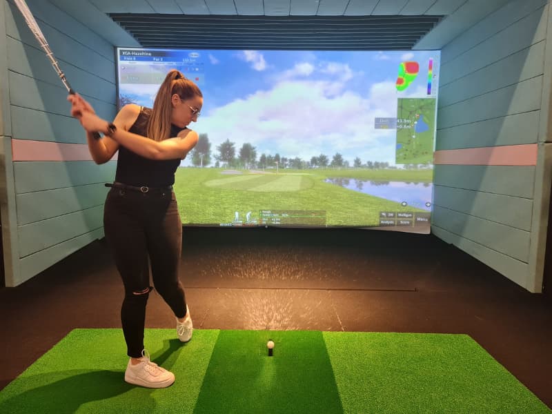 Image of Nadia teeing off at X-Golf Balcatta. She is mid swing hitting a ball at the screen