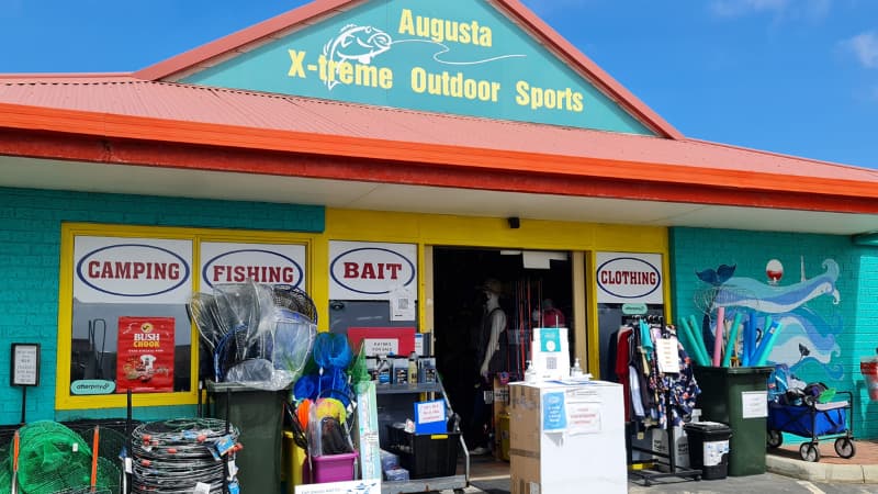 Image of Augusta X-Treme Outdoor Sports store. The shop is teal with a red roof and there is merchandise outside. 