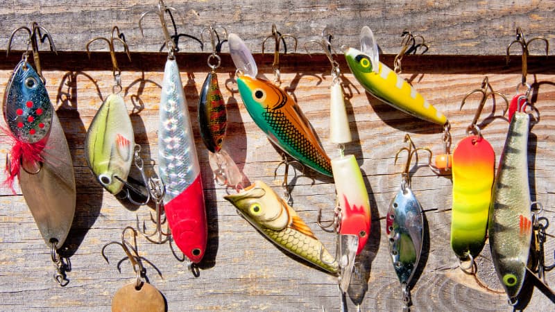 Image of assorted fishing lures laying on the wood plank of a jetty