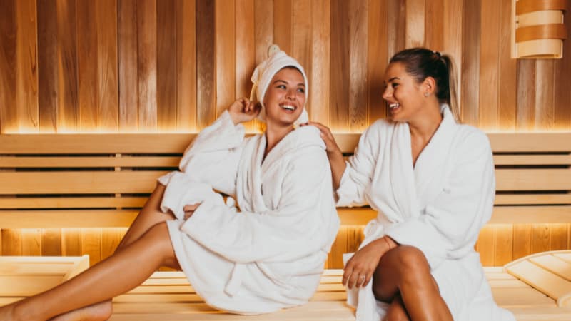 Two women sitting and laughing in sauna