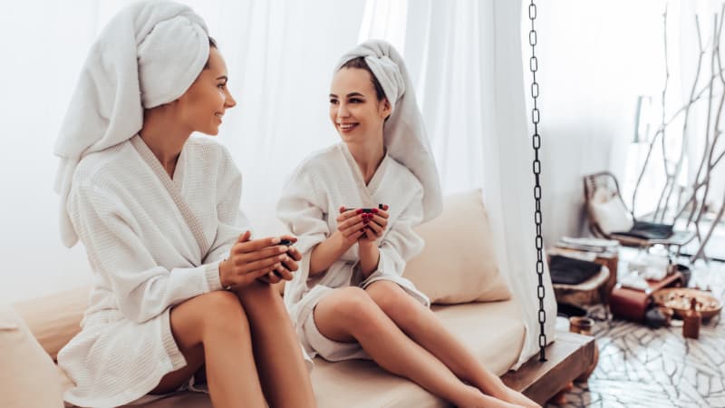 Two women wearing towels drinking tea in a spa