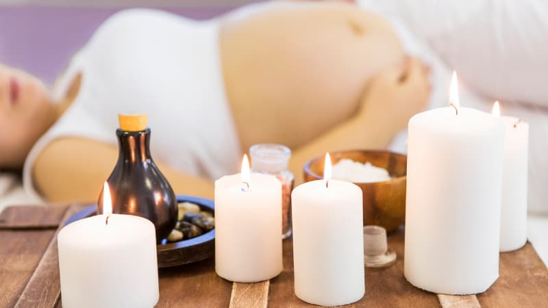 Woman laying on massage table with candles burning in the foreground.