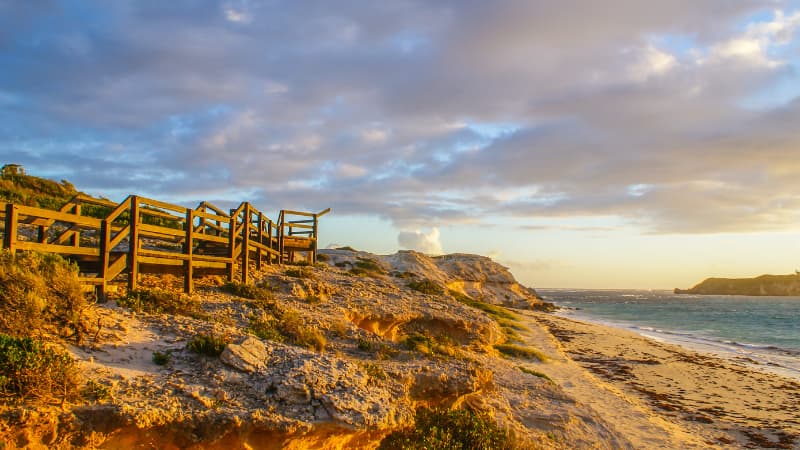 Hamelin Bay Beach at sunset. There are wooden stairs leading to the beach to the left and ocean to the right