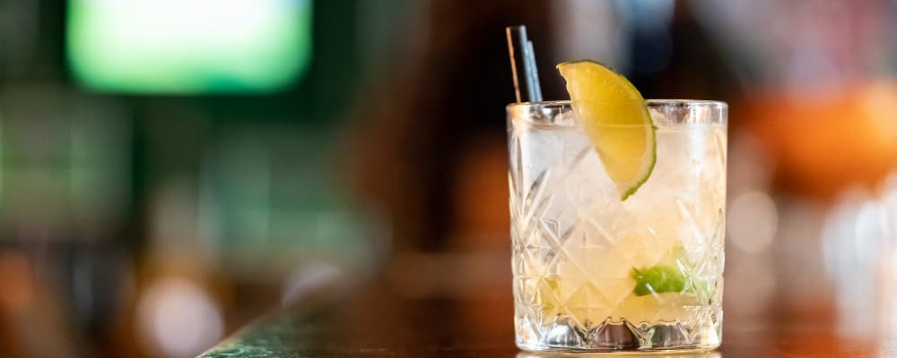 Image of a cocktail with lime wedge and out of focus background