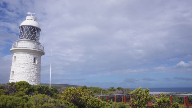 Cape Naturaliste Lighthouse on the left, shrubs along the bottom of the frame and a cloudy, overcast sky