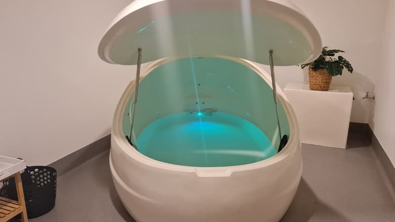 Float pod with glowing blue light in a float room at Clear Mind Studio