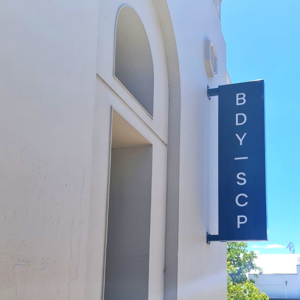 Blue sign outside building that reads BDY-SCP