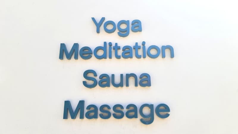 Blue text on outside of the Bodyscape building that reads "Yoga, Meditation, Sauna, Massage"