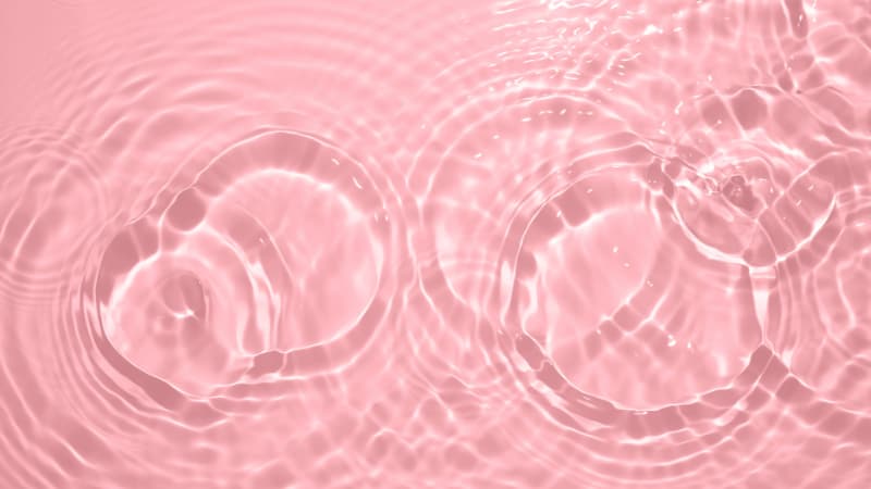Circular water waves over a light pink background