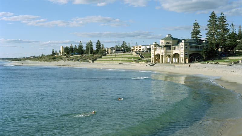 Shoreline of Cottesloe Beach in Perth, there are two people swimming in the water