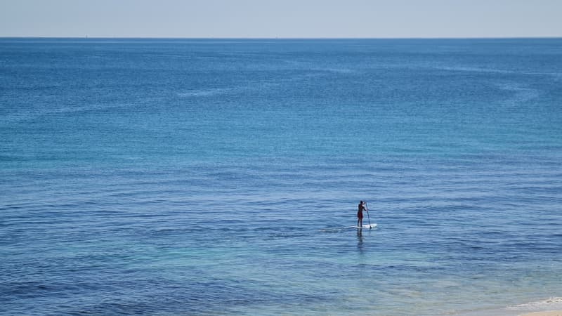 A stand up paddle boarder glides through the water at Cottesloe