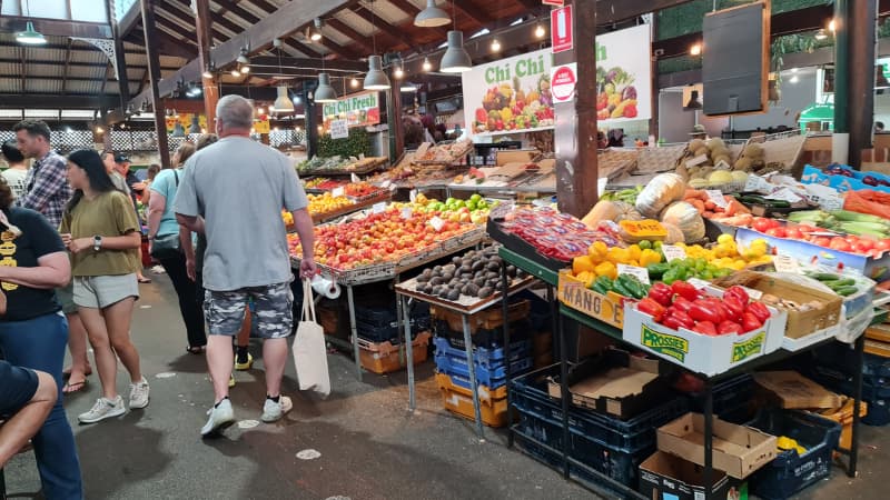 People walking through fruit and vegetable stalls at Fremantle Markets