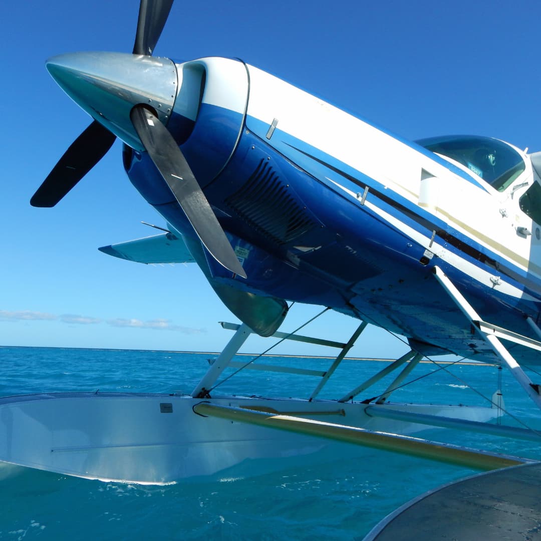 Close-up of the nose of a blue seaplane landing on the ocean