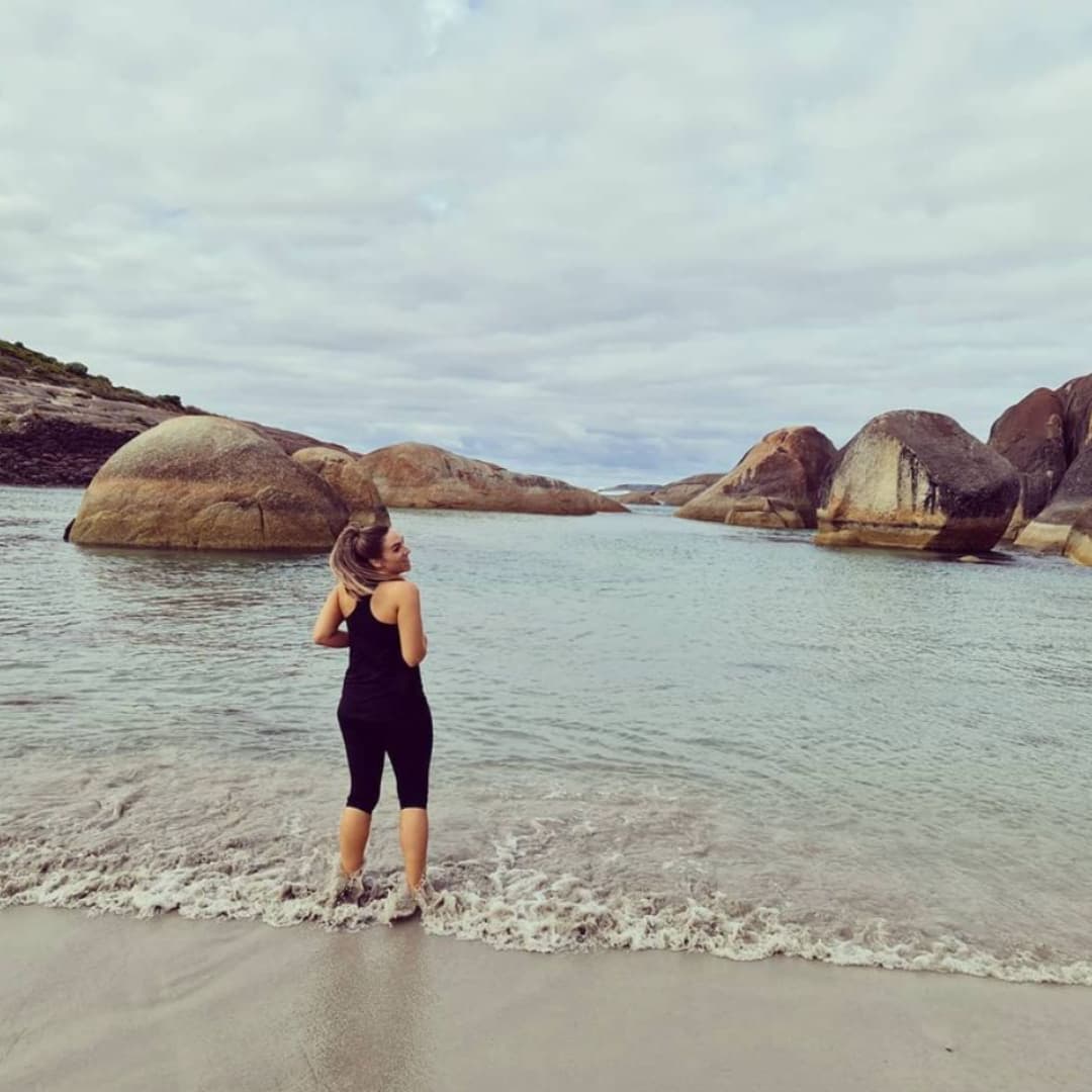 Nadia stands in ankle-deep water at Elephant Rocks in Denmark Western Australia