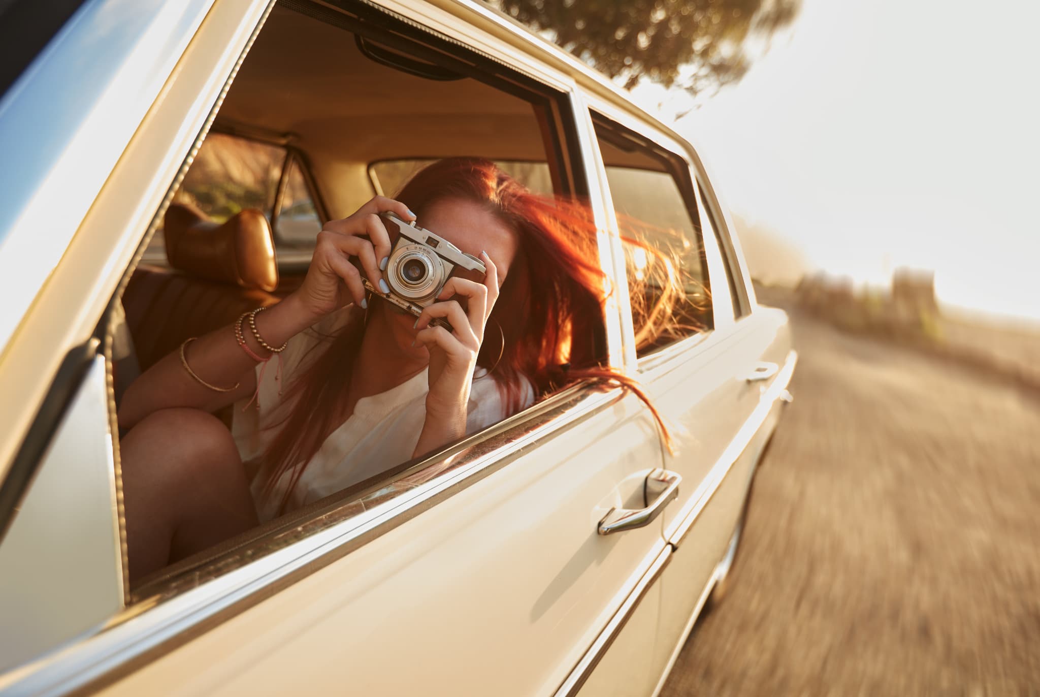 Woman on a Perth summer road trip leans out of a car window to take a picture