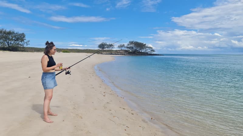 Nadia standing on a beach fishing