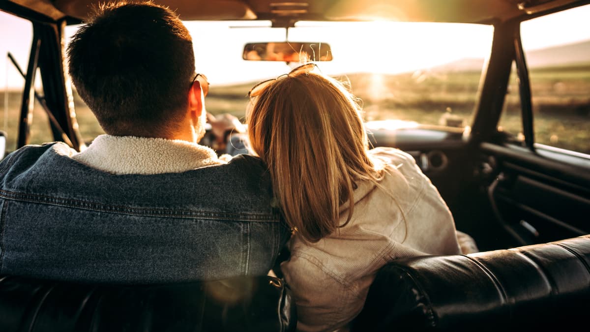 Woman rests her head on her partners shoulder on a road trip.