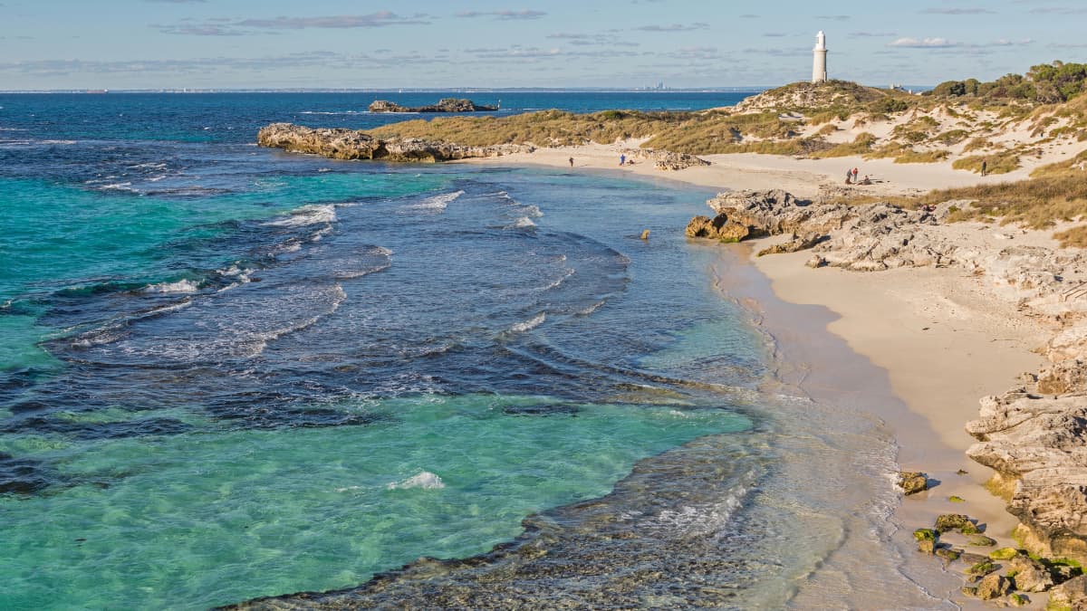 Rottnest Island Scenic coastal view of Rottnest Island with turquoise water, sandy beach, and lighthouse in the distance