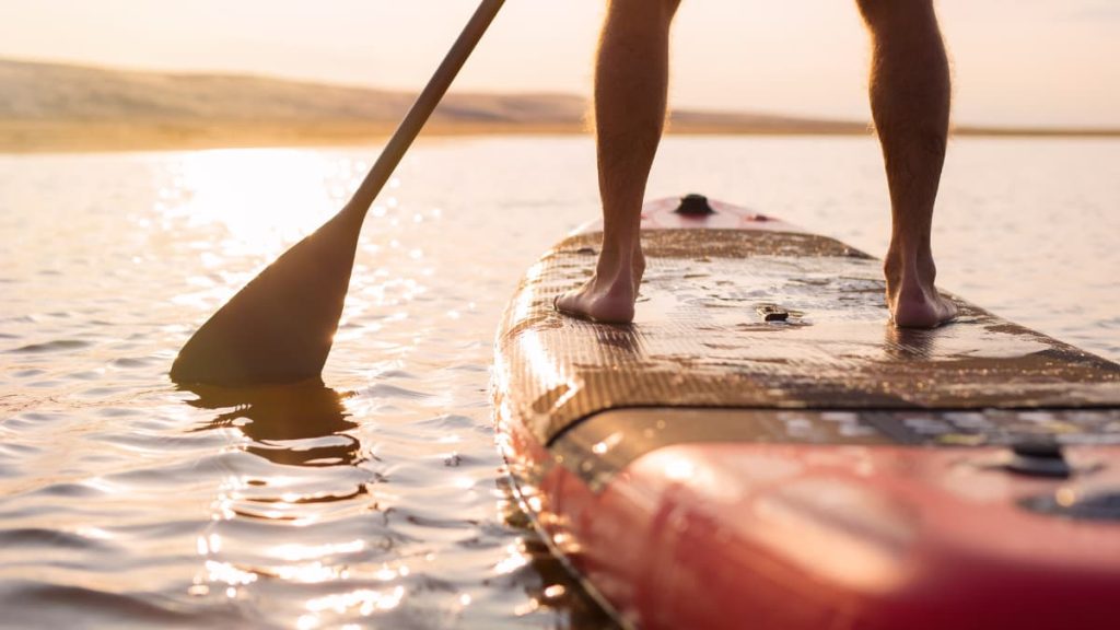 Person stand-up paddleboarding at sunset on calm water