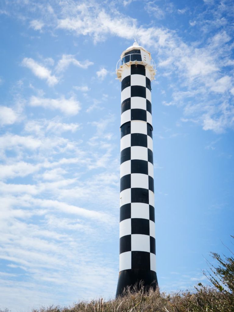 Close-up view of the black-and-white striped Bunbury Lighthouse against a bright blue sky with scattered clouds in Bunbury, Western Australia.